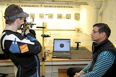 Juho Autio ampuu ilmakiväärillä noptel-testiä Jukka Salosen seuratessa näytöltä ampujan työskentelyä.