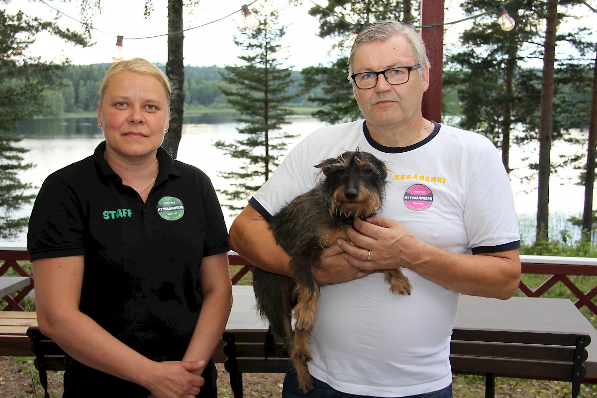 Nyyssänniemen terassilta avautuu näköala Keurusselälle. Jonna Salon ja Paavo Ässämäen mielestä näköala on yksi Suomen suven upeimpia. Vieraiden vastaanottoon erikoistunut Sly-koira on maisemasta samaa mieltä.