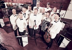 Juha Hostikan johtama 11-henkinen Dallapé-orkesteri tulee sunnuntaina Pukkilansaaren lavalle. Luvassa on musiikillinen läpileikkaus Suomen historiaan ja identiteettiin.