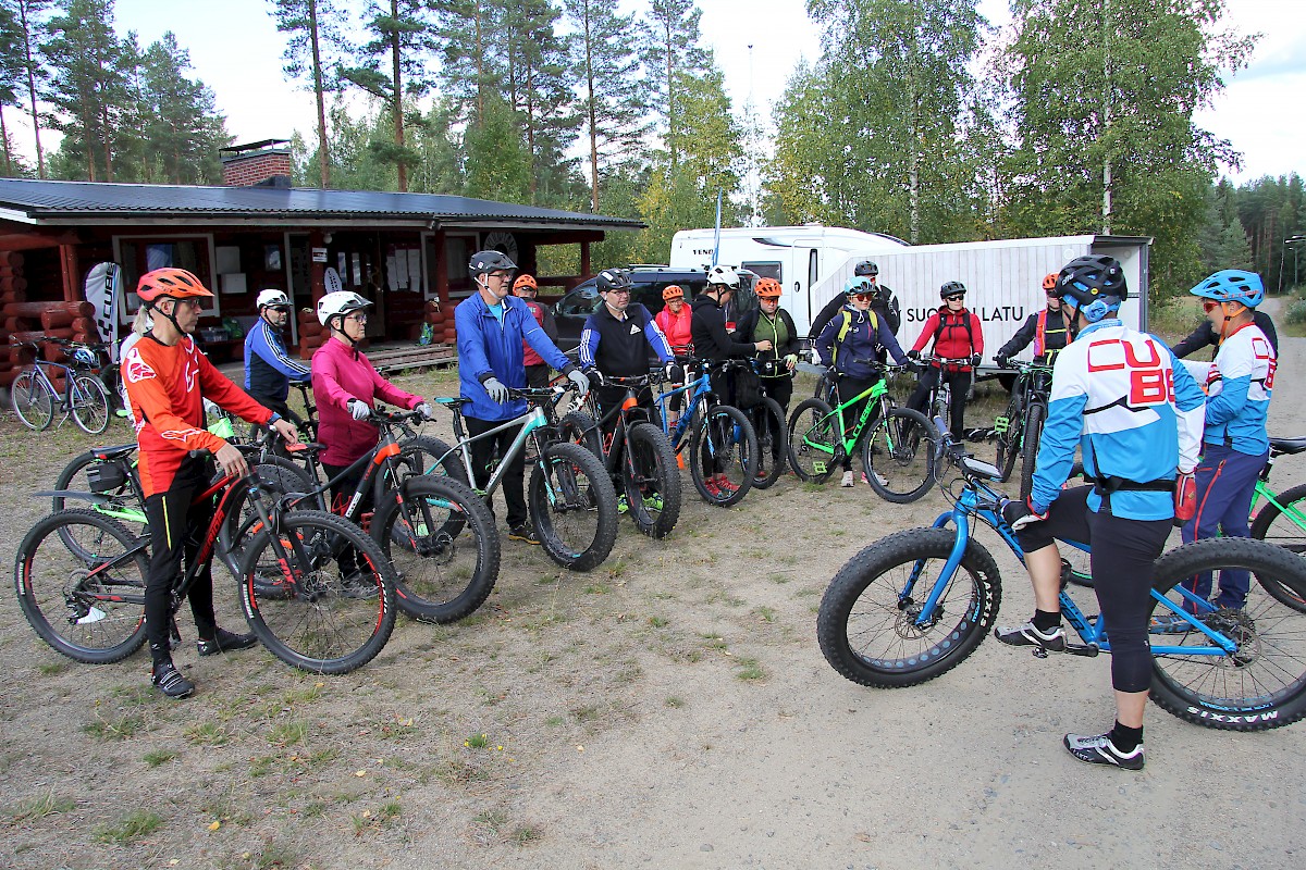 Maastopyöräily tutuksi -illan osanottajat Ampumarata Kympin edustalla kuulemassa Tiina Riikosen ja Matti Luomalan (sinipuseroiset kuvassa oikealla) ohjeita.