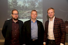 Sami Logren, Jarmo Pienimäki ja Heikki Riitahuhta ovat tyytyväisiä matkailualueen kehityssuunnitelmiin. Kuvassa taustalla havainne kuva rantarakentamisen mahdollisuuksista.