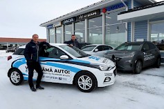 Arto Ulvinen ja Petri Nikkilä Arton Auton juhlavuoden Facebook-arvottavan Hyundai i20 -auton äärellä. Kuvassa taustalla latauksessa Hyundai Kona electric -täyssähköhenkilöauto.