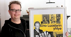 Hannu Luostari esittelee tanssijulistetta, jonka pääkuvassa nuori maestro Eino Luostari pitää harmonikkaa sylissään. Pikkukuvassa oikealla puolella on Director musices arvonimi jo myönnetty hänelle. Kuva: Masa Kojola.