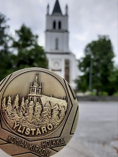 Komian kirkon hölkän mitalissa on kuvattu myös Ylistaron kirkko.