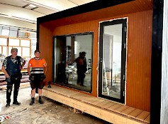 1. Entrepot Trade Oy:n toimitusjohtaja Topias Riiho sekä hänen isänsä Jukka Riiho esittelevät pihasaunaa. Topias Riiho myöntää, että pihasauna on ylellisyystuote, jossa variaatioita löytyy asiakkaista riippuen. Kuvan sauna on täysin valmiina ja sähköistettynä tilattu.