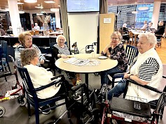 Kuvassa Saga Lakeudenlinnan iloinen naisporukka, jonka joukossa kukkapaitainen Tuula Saari vielä iloitsee ääneen että ”se on hienoa, kun johtajakin tulee meille päivittäin juttelemaan”.