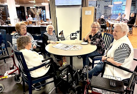 Kuvassa Saga Lakeudenlinnan iloinen naisporukka, jonka joukossa kukkapaitainen Tuula Saari vielä iloitsee ääneen että ”se on hienoa, kun johtajakin tulee meille päivittäin juttelemaan”.