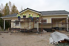 Sedu Ähtärin rakennusalan opiskelijat telineillä valmiina maalaamaan räystään aluslaudoitusta.