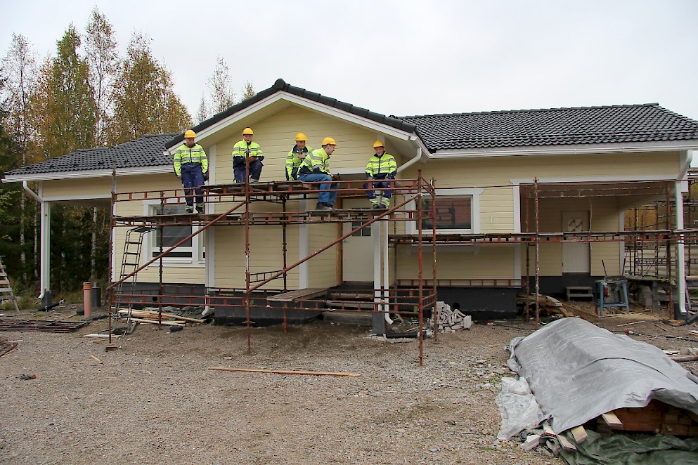 Sedu Ähtärin rakennusalan opiskelijat telineillä valmiina maalaamaan räystään aluslaudoitusta.