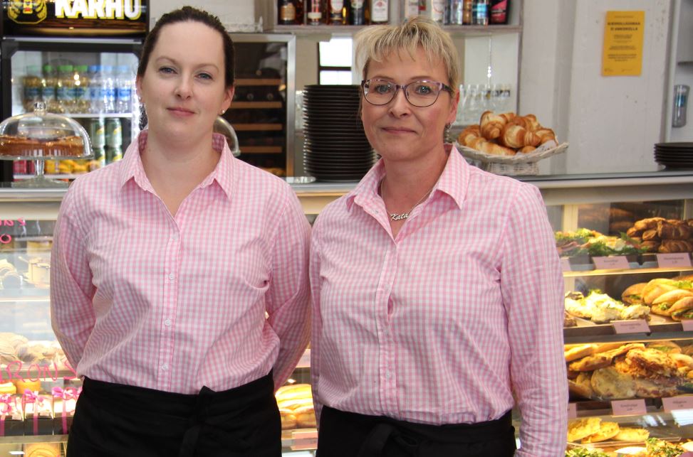 Johanna Luiro-Ojasen ja ravintolapäällikkö Katariina Saarilahden takana olevista vitriineistä löytyy runsas valikoima suussa sulavia leivontatuotteita.