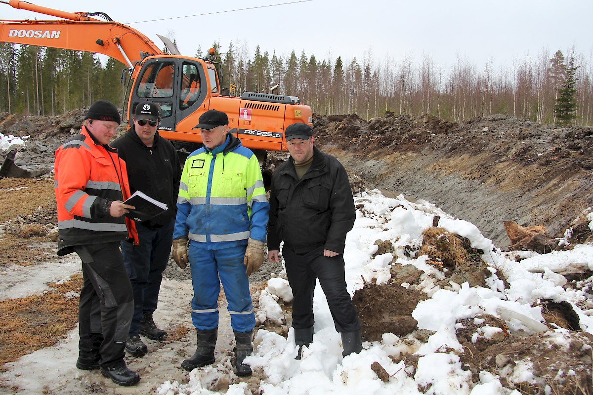 Kuvanottohetkellä työkohde oli Valkeisennevan luomalla Markus Perälän maalla, jossa Timo Loukasmäen koneen edustalla ovat koneyrittäjä Raine Sirèn, kuljettaja Mikki Hietaharju, Risto Perälä ja Raimo Ekman. Takana olevan luoman syvyys on lähes kolme metriä.